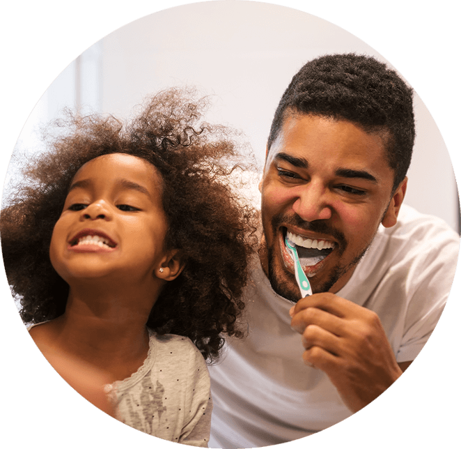 daughter and father brushing teeth in mirror