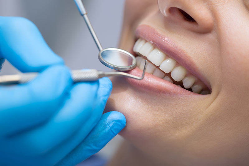 Close up photo of a woman flossing her teeth.