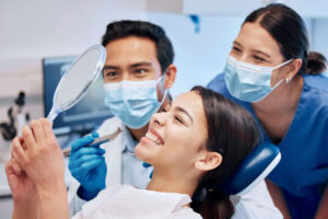 patient looking in mirror as a dentist admires they're work